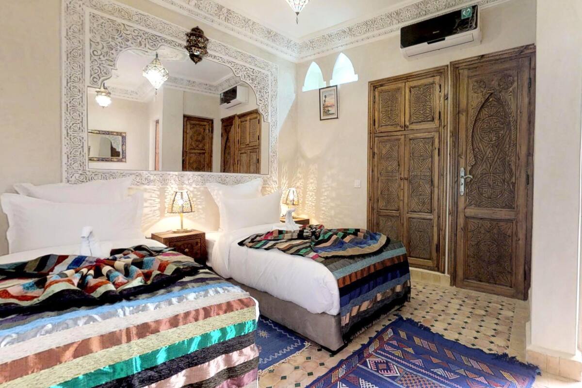 A traditional room with two beds, ornate wooden doors, and patterned rugs.