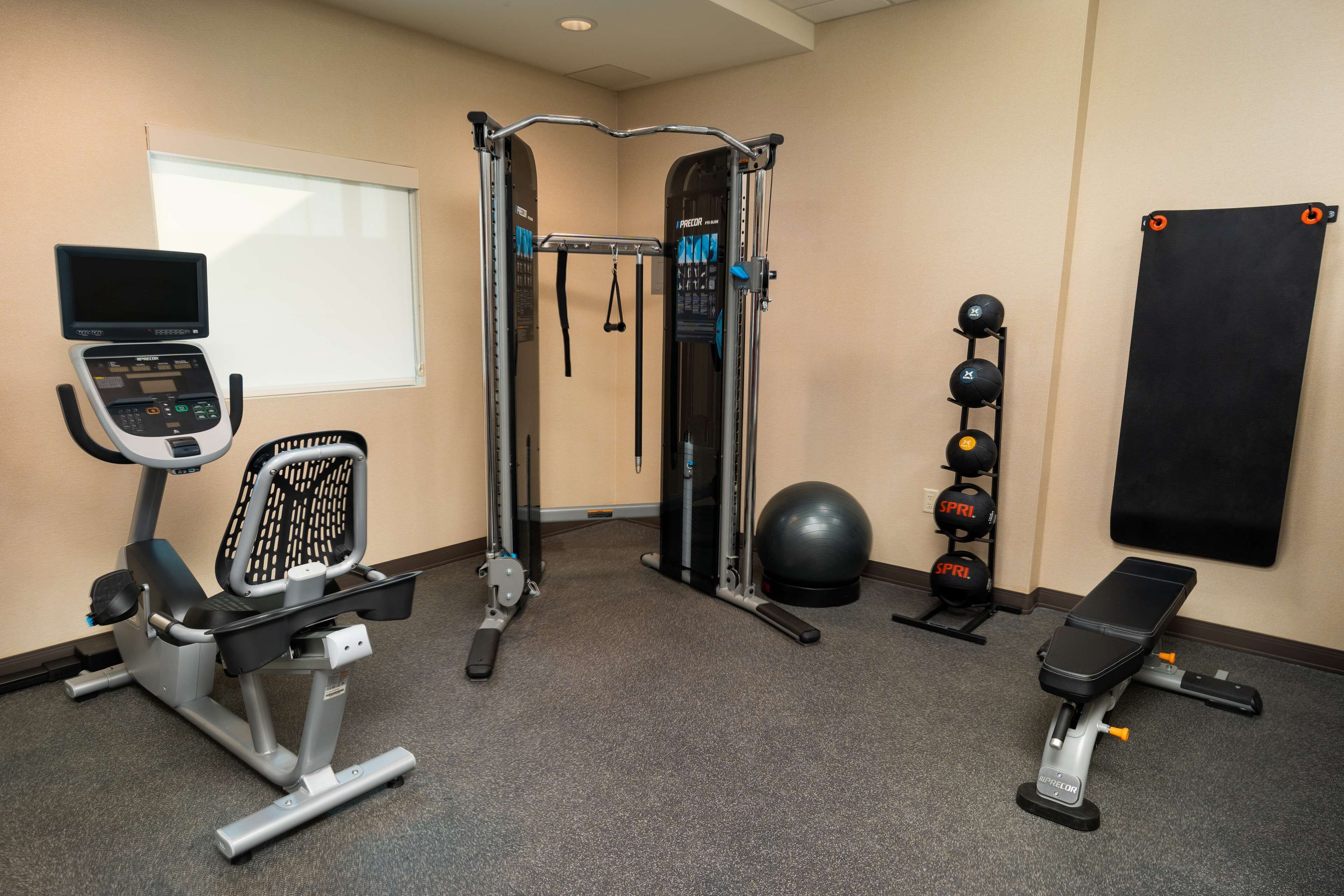 A gym with exercise equipment including a treadmill, a weight machine, a pull-up bar, and a bench.