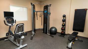 A gym with exercise equipment including a treadmill, a weight machine, a pull-up bar, and a bench.