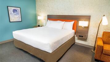 A hotel room with a large bed, two bedside lamps, a nightstand, and a chair.