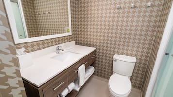 Un baño con lavamanos, espejo y retrete blancos.