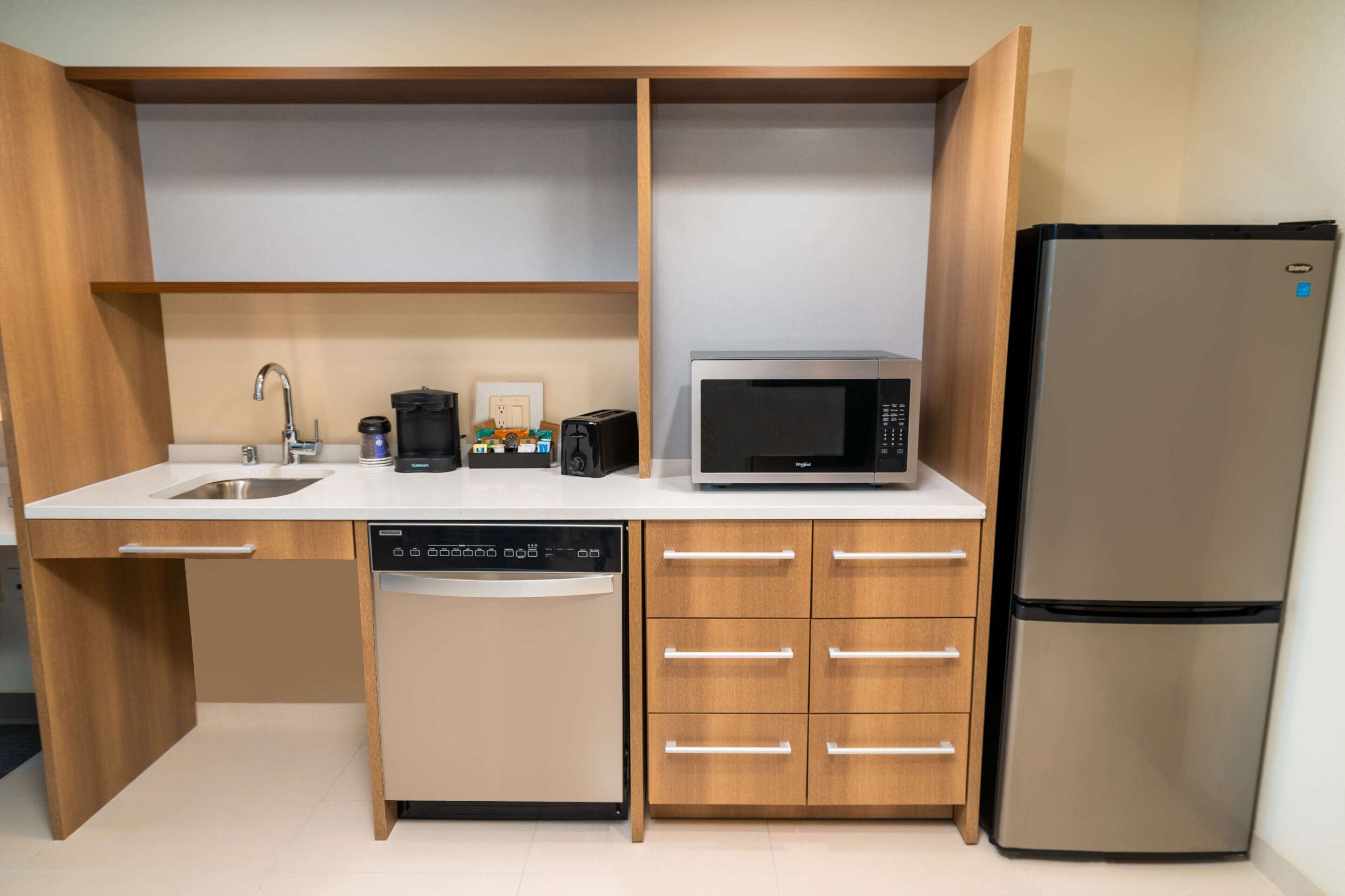 A compact kitchen with a dishwasher, microwave, and refrigerator.