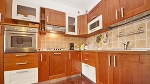 A kitchen with wooden cabinets, stainless steel appliances, and a tiled backsplash. - Vista Lago (Padenghe sul Garda)