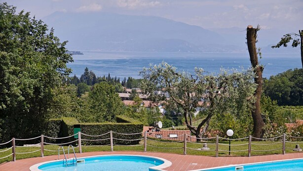 A swimming pool with a heart-shaped design, surrounded by a brick deck and a rope fence. - Vista Lago (Padenghe sul Garda)