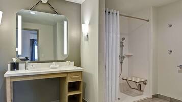 A modern bathroom with a large mirror, a sink, and a shower area.