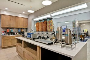 Una barra de desayuno moderna con máquinas expendedoras de café, cereales y leche.