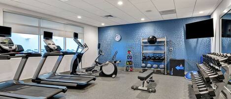 A modern gym with treadmills, an elliptical, and weightlifting equipment.