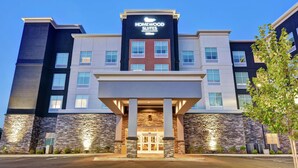 Um hotel com fachada moderna, um letreiro chamativo para Homewood Suites e uma entrada revestida em pedra.
