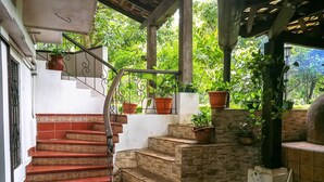 A staircase with red and beige steps leading to a covered area with potted plants. - Hostal Las Marias (Taxisco)