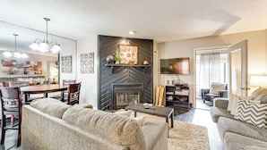 Una sala de estar con chimenea, sofá, mesa de centro y televisor.