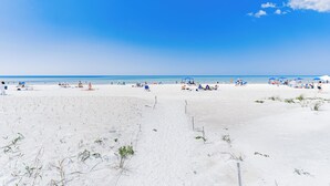 A beach with people sunbathing and swimming, and a clear blue sky.