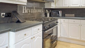 A kitchen with white cabinets, a gas stove, a microwave, and a sign that says "Money isn't everything but it helps keep the kids in touch." - 5 bedroom accommodation in Glandwr, near Narbeth (Glandwr, near Narbeth)