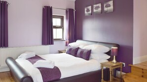 A bedroom with a bed, a nightstand, a window with curtains, and a wall with three framed pictures. - 5 bedroom accommodation in Glandwr, near Narbeth (Glandwr, near Narbeth)