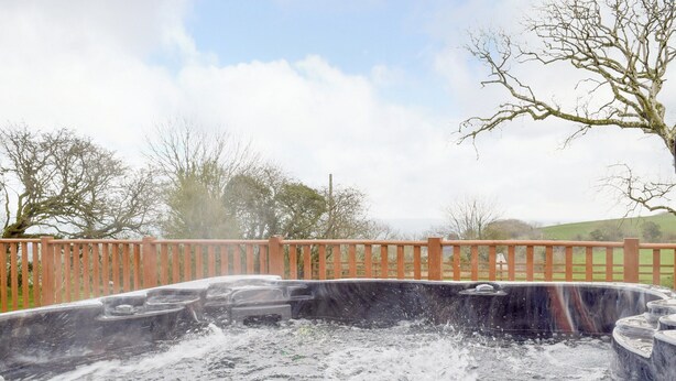 A hot tub with a wooden deck and a view of trees and hills. - 5 bedroom accommodation in Glandwr, near Narbeth (Glandwr, near Narbeth)