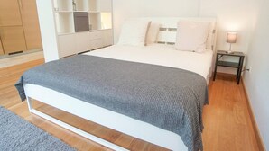 Een slaapkamer met een bed, nachtkastje, lamp en inbouwkast.