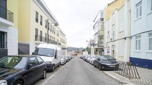 Een geplaveide straat met geparkeerde auto's en meerlaags gebouwen met balkons.