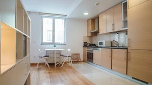 Een moderne keuken met houten kastjes, een eettafel met stoelen en een raam dat natuurlijk licht binnenlaat.