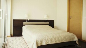 A bedroom with a bed, a wooden headboard, a door, and a window. - Vacation Home 2 Bedroom Luxury Home With Pool in Patroves (Albufeira)
