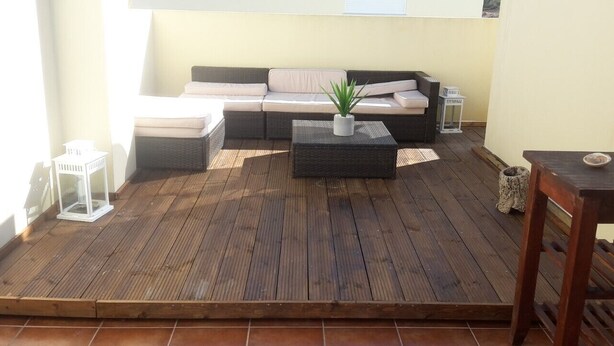 A wooden deck with a sofa, a small table, and a potted plant. - Vacation Home 2 Bedroom Luxury Home With Pool in Patroves (Albufeira)