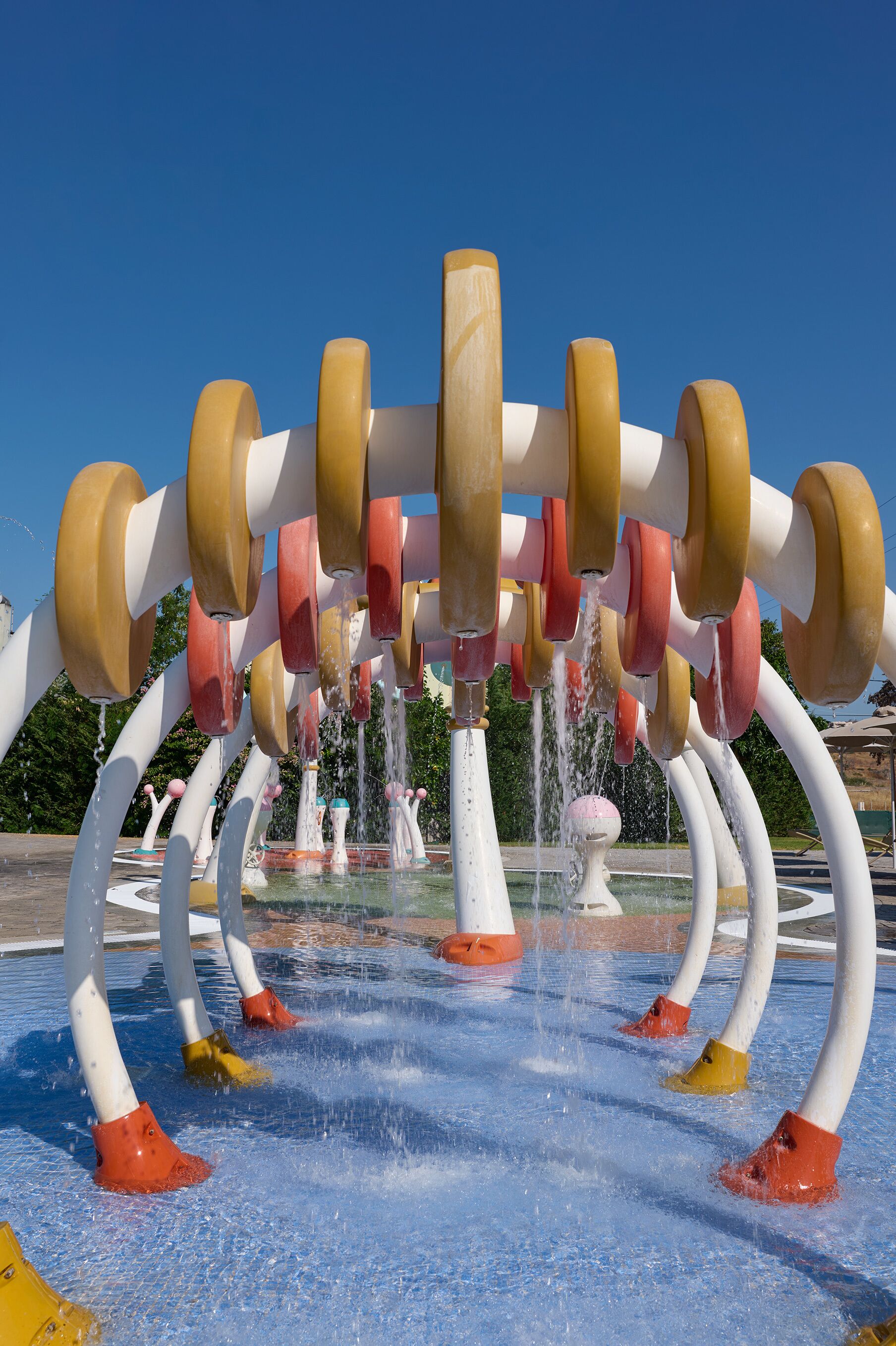 A water fountain with multiple nozzles and a clear blue sky in the background.