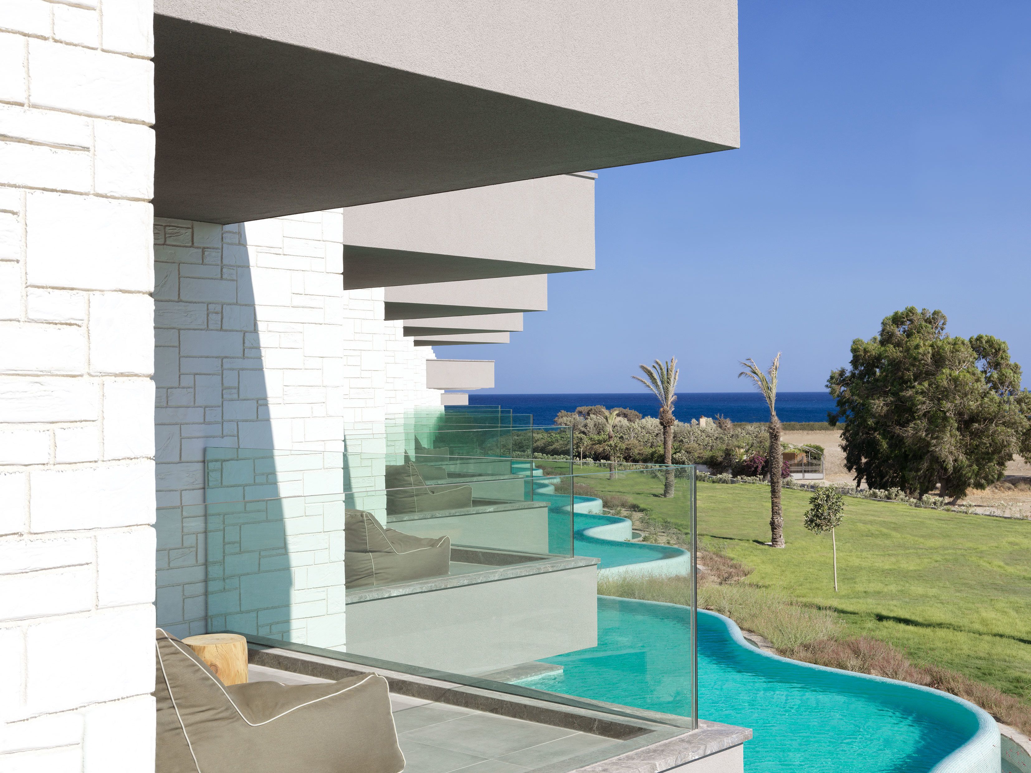 Un edificio moderno con una piscina infinita de vidrio y vistas al océano.