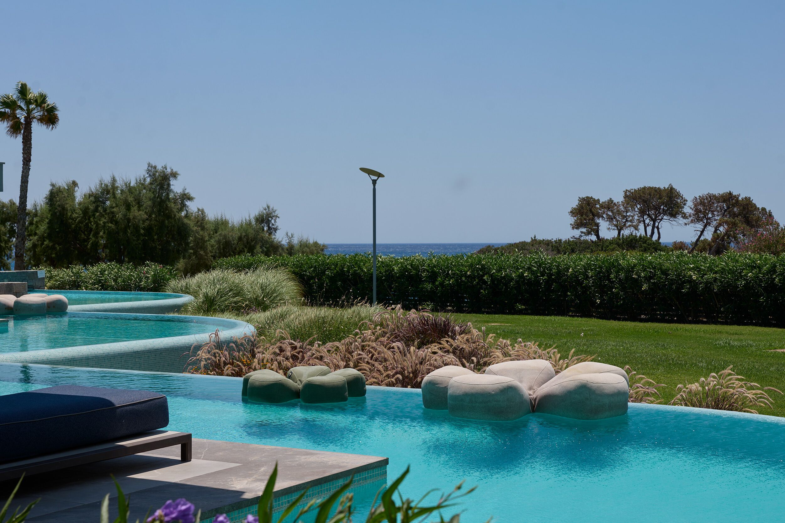 A swimming pool with multiple seating areas and a view of the ocean.