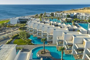 A resort with multiple white buildings, a central swimming pool, and a view of the ocean. - Atlantica Dreams Resort - All Inclusive (Rhodes)