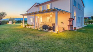 A two-story house with a covered patio, outdoor seating, and a barbecue area.