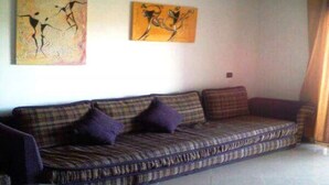 Un salon avec un canapé à carreaux, deux coussins et deux tableaux abstraits accrochés au mur.