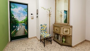 A room with a door featuring a scenic mural, a chair, a mirror, and a decorative cabinet. - Elegant apartment located in the heart of Palermo, equipped with all comforts. (Palermo)