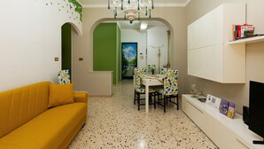 A dining area with a table and chairs, a chandelier, and a sofa. - Elegant apartment located in the heart of Palermo, equipped with all comforts. (Palermo)