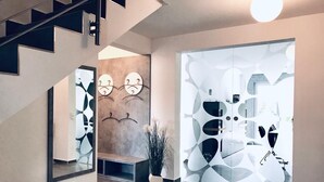 A modern interior with a staircase, a wall-mounted mirror, abstract wall art, and a glass partition with a geometric pattern. - Dream vacation, luxury and relaxation with your own pool and sauna  (Kalkhorst)