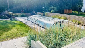 A greenhouse structure with a transparent roof, surrounded by a grassy area and a concrete pathway. - Dream vacation, luxury and relaxation with your own pool and sauna  (Kalkhorst)