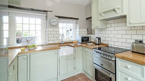 Una cucina con mobili bianchi, un forno a microonde, un bollitore e un forno.