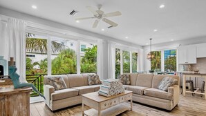 A spacious living area with a large sectional sofa, a wooden coffee table, and a ceiling fan.