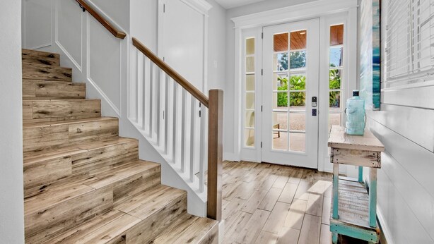 A staircase with wooden steps and white railings leading to a room with a white door and glass panels.