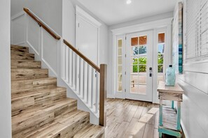 A staircase with wooden steps and white railings leading to a room with a white door and glass panels. - Beach Escape! Luxury Home with Pool, Spa, Rooftop Deck and Walk to Beach (Anna Maria)