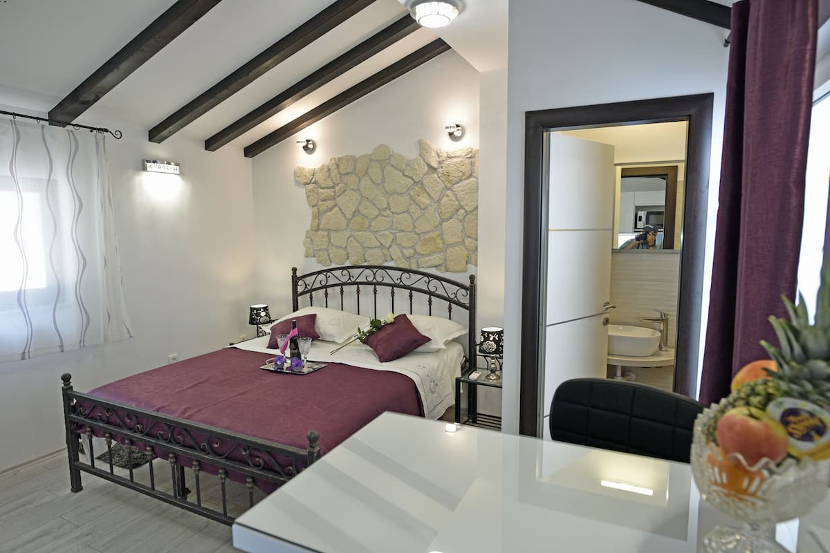 A bedroom with a bed, bedside tables, a mirror, and a view into the bathroom.