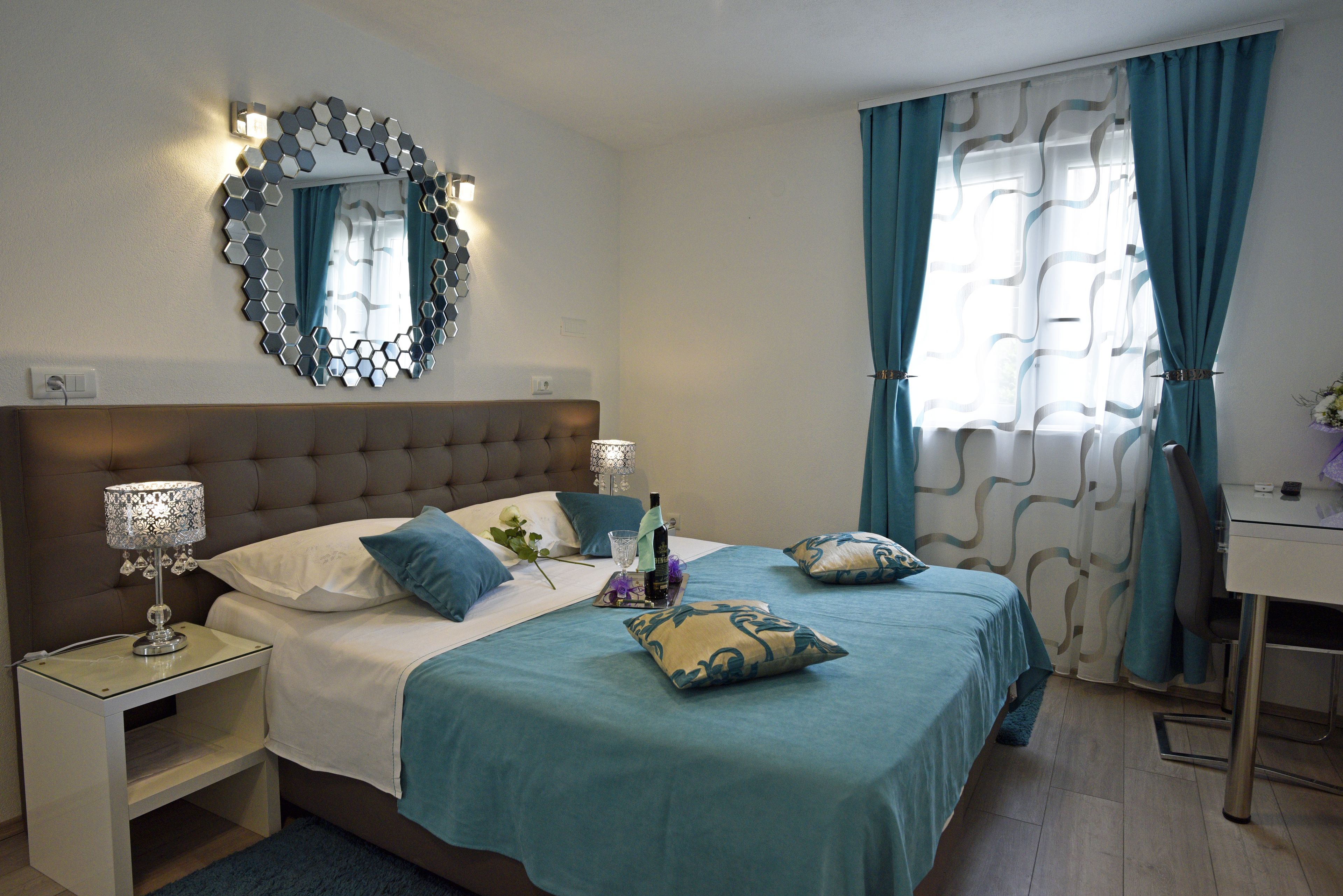 Une chambre bien rangée, avec un lit, des tables de chevet, un bureau et une fenêtre avec des rideaux.