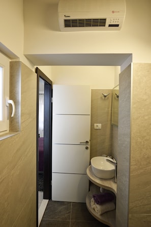 Un baño pequeño con un lavamanos blanco, un espejo y un perchero para toallas.