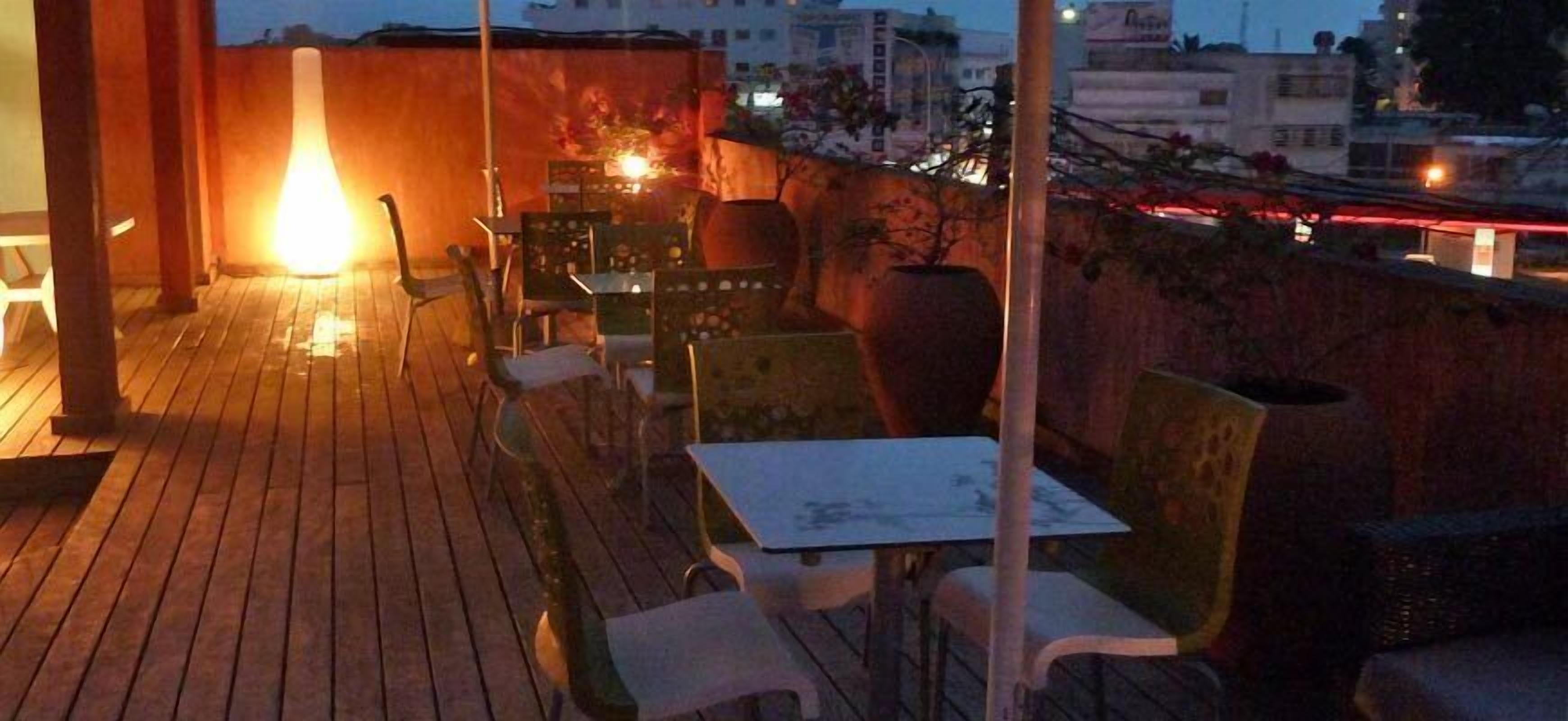 Une terrasse extérieure dotée d’un plancher en bois, de chaises et de tables en métal.
