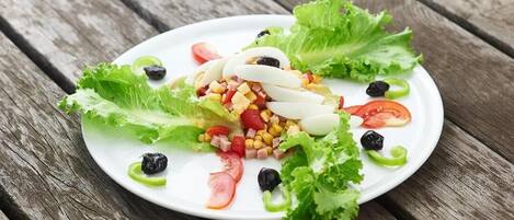 A white plate with a salad on a wooden table.