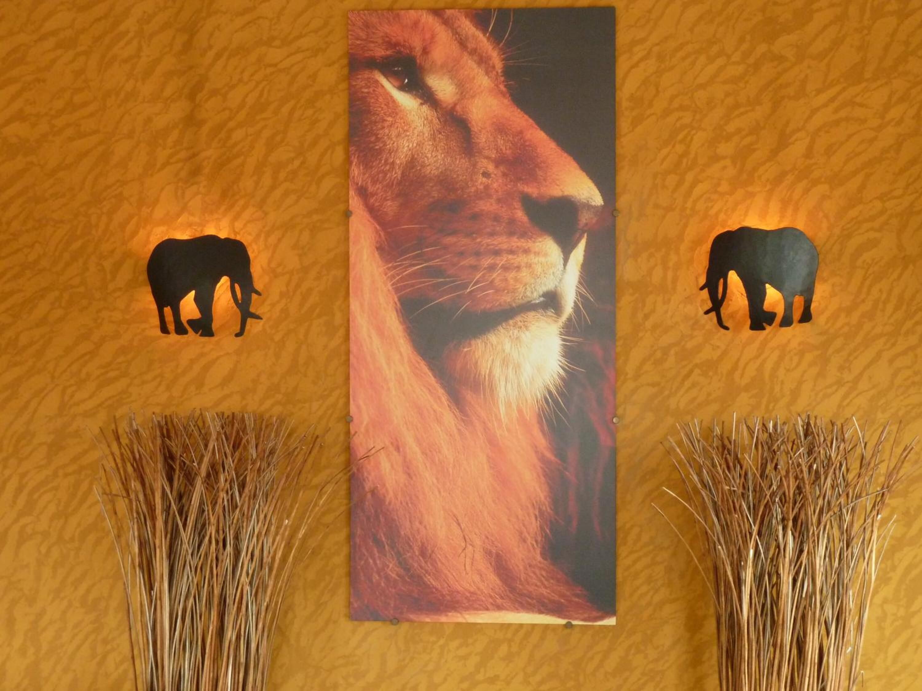 A wall with a large animal portrait and silhouettes of elephants.