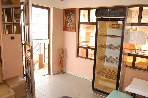 Una habitación con un gran ventanal abierto hacia el exterior, una ventana con vistas y un refrigerador con papeles encima.