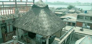 Una estructura con techo de paja y piso de baldosas, rodeada por un balcón con barandilla.