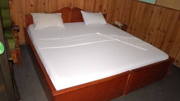 Un lit en bois recouvert de draps blancs, dans une pièce aux murs lambrés.