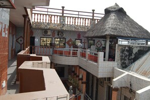 A multi-level building with a thatched-roof structure, tiled walls, and a balcony with a railing. - Benin Hotel Terminus (Cotonou)