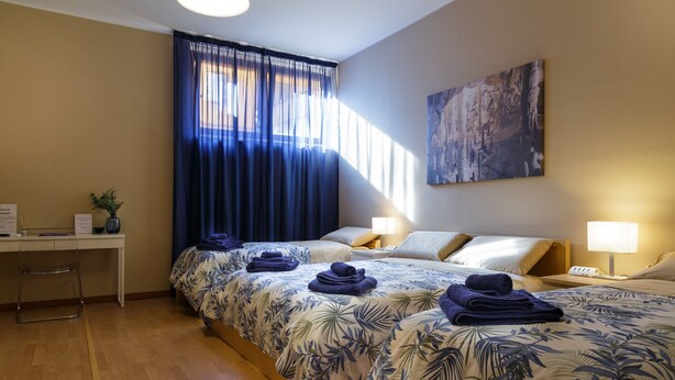 A hotel room with two beds, a desk, and a chair. - Juliette Rooms (Jesi)