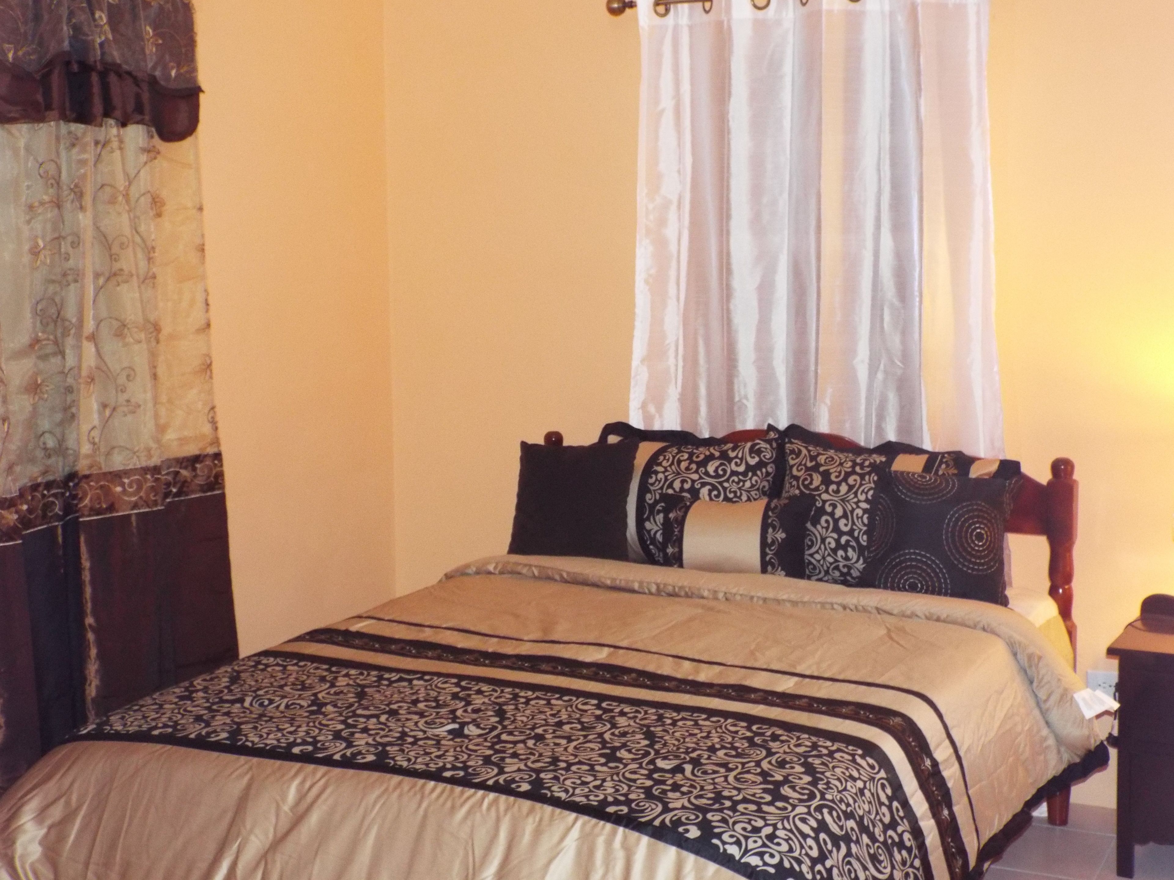 Una cama con una colcha estampada, un cabecero de madera y un dosel con cortinas vaporosas.