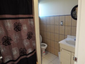 Um banheiro com vaso sanitário, pia e cortina de chuveiro estampada com flores.